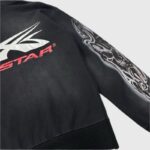 Close-up view of the Hellstar Airbrushed Skull Hoodie sleeve showing the custom skull graphic and logo branding detail.