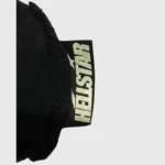 A detailed close-up of the official Hellstar logo tag sewn onto a premium black knit beanie for authentic branding.