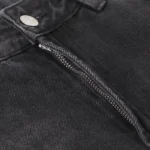 Close-up view of the metallic button and zipper hardware on Hellstar black denim flare streetwear jeans.