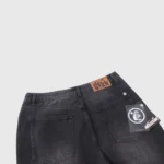 Close-up of the Hellstar black denim flare jeans featuring the branded leather waist patch and product swing tag.
