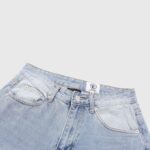 Close-up of the waist area of vintage washed Hellstar Black Flame denim jeans featuring button and pocket detail.