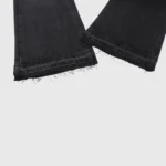 Detailed close-up view of the raw, distressed hem on a pair of premium Hellstar black washed denim jeans.