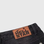 Hellstar black washed denim jeans featuring a premium leather logo patch on the waistband for a vintage streetwear look.