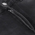 Close-up of Hellstar black washed denim jeans featuring a prominent metallic zipper detail on the fly area.