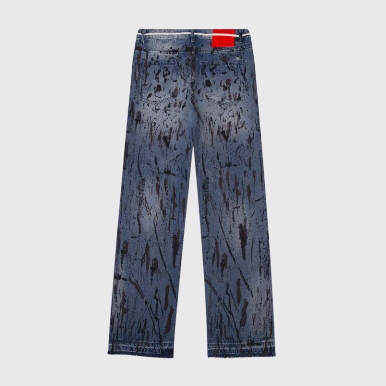Back view of Hellstar premium denim jeans in a vintage blue wash featuring a unique black paint splatter pattern.