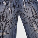 Detailed close-up view of Hellstar blue denim jeans featuring unique black graphic prints and distressed textures.