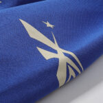 Close-up view of the distinctive white logo graphic printed on the vibrant blue Hellstar No Guts No Glory hoodie.