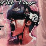 Pink Hellstar Brainwashed World Tour t-shirt graphic showing a person wearing a VR headset with branding detail.