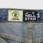 Close-up view of the Hellstar Capsule 9 denim shorts branding tag and authentication label on washed blue denim fabric.