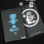 Close-up view of the Hellstar Cotton Mask graphic t-shirt showing authentic branding, logo tags, and detailed print.