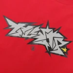 Close-up view of the unique distressed crack print graphic detail on a red Hellstar cotton streetwear t-shirt.