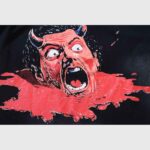 Close-up graphic print of the Hellstar Devil Ozzy t-shirt featuring a screaming demon face on a red blood splatter.