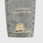 Close-up view of premium Hellstar grey distressed denim jeans featuring unique frayed fabric texture and washed finish.