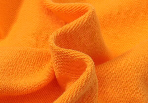 Close-up view of the premium vibrant orange cotton fabric texture from the Hellstar Fire Orange Dye Tracksuit.