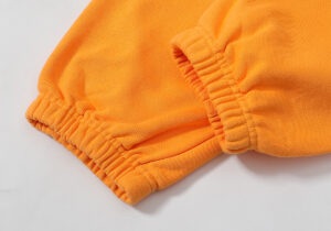 Close-up view of the elastic ribbed ankle cuff detail on the vibrant orange Hellstar streetwear sweatpants.