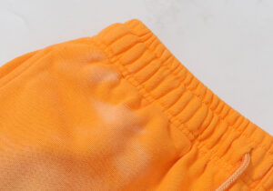 Close-up of the elastic waistband on the vibrant fire orange Hellstar sweatpants featuring a drawstring closure.
