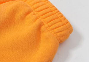 Close-up view of the ribbed elastic waistband on the vibrant Hellstar Fire Orange Dye cotton tracksuit sweatpants.