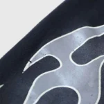 Close-up view of the distinctive flame graphic printed on the black cotton fabric of Hellstar flame sweatpants.