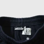 Close-up view of the interior label and branding details on black Hellstar Flame sweatpants for authentication.