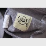 Close-up of the Hellstar Future Flame hoodie interior brand tag featuring the NFC authentication logo on grey fabric.