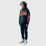 A male model wearing a dark grey Hellstar Future Flame hoodie featuring unique graphic flame sleeve prints.