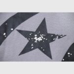 Detailed view of the black star print with distressed white paint spots on the grey Hellstar Future Flame hoodie.