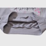 Close-up view of the ribbed hem and pink and black flame graphic details on a grey Hellstar Future Flame hoodie.