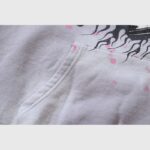 Close-up view of the grey Hellstar Future Flame hoodie featuring a front kangaroo pocket and pink and black flame graphics.