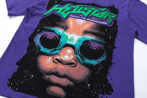 Close-up graphic print on the front of a purple Hellstar Goggles t-shirt featuring a face wearing sci-fi goggles.