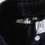 Close-up view of the interior brand label and size tag on a black pair of Hellstar Graffiti sweatpants.