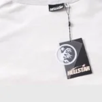A close-up view of a Hellstar gray graphic print tracksuit featuring branded neck and product hang tags.