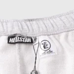 Close-up view of the internal brand tag and authentication label on a gray Hellstar graphic print tracksuit.