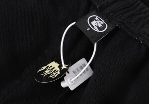Close-up view of a Hellstar clothing branding tag and flame logo hangtag on a premium washed black fleece hoodie.