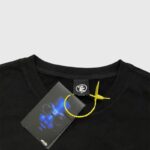 Close-up of the Hellstar Horror Book T-shirt neck label and branded hang tag on black premium cotton fabric.
