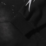 Close-up view of the sleeve detail on a black Hellstar Hstar tracksuit hoodie featuring white airbrush graphics.