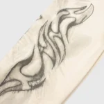 Close-up detail of the graphic print on the cream Hellstar HStar Records hoodie featuring unique artistic flame motifs.