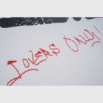 Close-up view of the Lovers Only red handwritten script graphic on the Hellstar I Love LA cotton streetwear T-shirt.