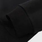 Closeup of black Hellstar Jason mask hoodie ribbed cuff and vintage-washed fleece fabric detail for product page