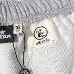 Close-up view of the interior authentication tag and size label on Hellstar Jupiter graphic grey terry cloth shorts.