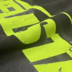 Close-up view of the neon green graphic screen print on a premium black Hellstar Marble Classic T-Shirt fabric.