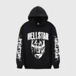 A black Hellstar hoodie featuring a large mask print graphic on the chest and branded sleeves in a streetwear style.