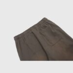 Close-up view of the back pocket detail on the brown Hellstar Mirror Faced sweatpants with an elastic waistband.