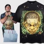 Man wearing a black Hellstar New Testament graphic t-shirt featuring an ancient tribal face and green accents.