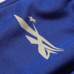 Close-up view of the Hellstar No Guts No Glory tracksuit blue fabric showing the detailed white brand logo graphic.