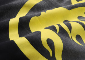 Close-up of the Hellstar No Guts No Glory hoodie in washed black cotton with a vibrant yellow graphic print detail.