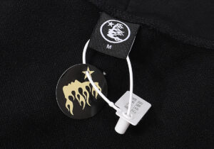 Close-up of the Hellstar No Guts No Glory Hoodie tag featuring the iconic flame star brand logo and size label.