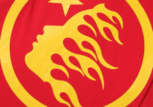 Close up view of the yellow graphic on a red Hellstar No Guts No Glory 100% cotton unisex vintage washed t-shirt.