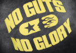 Close-up of the Hellstar No Guts No Glory sweatpant featuring a yellow graphic print on black fabric with a star logo.