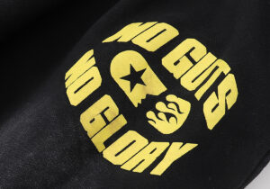 Close-up of the Hellstar No Guts No Glory tracksuit in black featuring a bold yellow graphic print on the fabric.