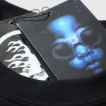 Detailed view of the Hellstar Paradise Girls T-shirt tag featuring a vibrant blue alien graphic and brand logo.